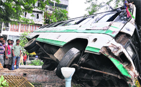 People look at a city bus that veered off the road after the driver lost control in Guwahati on Sunday.
