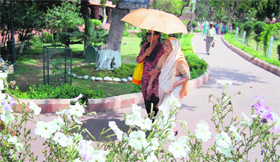 Two women visitors protect themselves from the scorching heat with an umbrella at the Jallianwala Bagh in Amritsar on Monday.