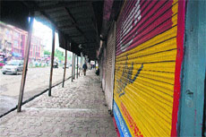  vehicles ply on a road next to closed shops during a strike in Srinagar on Monday