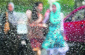 Women walk on a road during rainfall in Srinagar on Monday.