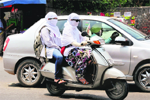Girls cover their faces with duppatas to protect themselves from scorching heat in Bathinda on Tuesday. 