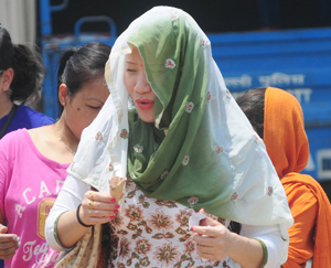 A woman covers her head with a dupatta in order to save herself from the scorching heat at India Gate in New Delhi on Wednesday. The maximum temperature in the city was recorded 41 degree Celsius.
