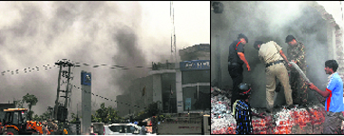 Smoke billows out of the basement of the automobile showroom; (right) firefighters try to douse the flames in Jalandhar on Wednesday.