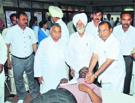 Dr Shiv Kumar, Civil Surgeon, tags a blood donation flag of the Red Cross Society to a donor during a blood donaton camp at Sant Nirankari Satsang Bhawan in Kurukshetra. 