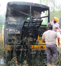 A fire brigade official tries to control fire in a prive bus at Dera Bassi on Friday.  