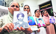 Nirmal Kaur (left) holds the portrait of her husband, subedar Assa Singh, who went missing while fighting during the 1971 Indo-Pak war, in Jammu on Friday. 