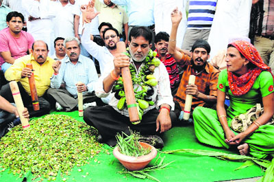 Former municipal councillor Vijay Kumar along with other residents of the city protests against the rising prices of vegetables in Bathinda on Sunday.