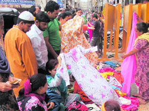 Locals purchase garments at a roadside stall at Raghnath Market in Jammu on Sunday. 