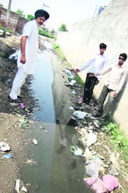 Villagers show stagnant water on a potholed road of Hargobindpura village near Ahmedgarh.