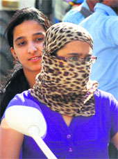  A girl covers her face to escape the rays of the sun while driving in jammu on Monday. 