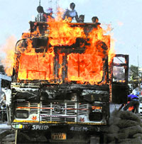 People unload foodgrains as an FCI truck catches fire at Naini bridge in Allahabad on Monday.