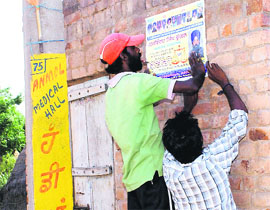Supporters paste the poster of a candidate on a wall in Rajpura on Monday. 