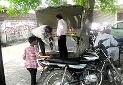 A team of health officials removes glow signs and posters of tobacco products from a booth on Bibiwala Road