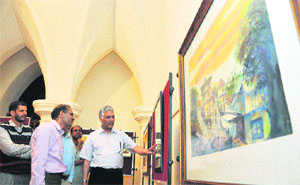 DK Gupta, Director, Language and Culture, has a look at a painting during an exhibition at the Gaiety Theatre in Shimla.