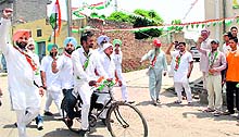 A Congress candidate rides a bicycle while canvassing in a Patiala village on Tuesday