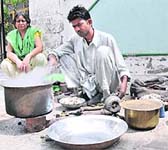 An artisan works on utensils while his wife looks on in Bathinda on Wednesday
