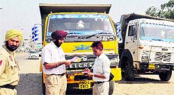 Police officials check the documents of a truck driver at Sohana village on Wednesday