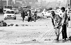 A man sprinkles water on tiles to keep dust at bay on the Zirakpur highway on Wednesday