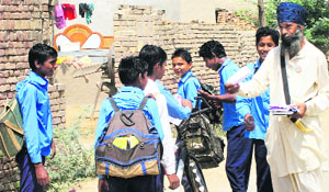 A supporter distributes pamphlets among schoolchildren in border Mauzam village on Wednesday. 