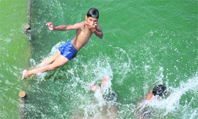 Children dive into the Brahm Sarover to beat the heat in Karnal.