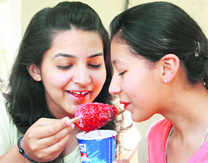Girls enjoy an ice candy in Jalandhar on Thursday.