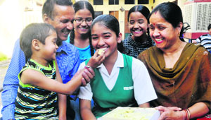 Kiran Aswal, a Class X student of St Xavier's High School, who has secured 85 per cent marks in the ICSE (Class X) examinations, celebrates her success with her family in Mohali on Friday. 
