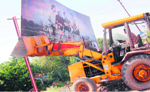 An illegal hoarding being removed by the Municipal Corporation in Haridwar on Friday.