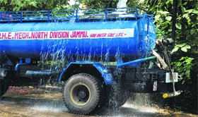 Drinking water goes down the drain as a tanker overflows in a water filling station in Jammu on Friday.
