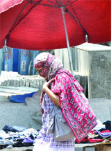 A girl covers herself with a cotton cloth while walking under the sun in New Delhi on Saturday. The temperature registers a record high for the month of May.
