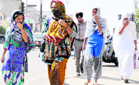 Girls cover their faces to escape the searing heat as mercury crossed 45C mark in Bathinda.