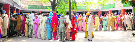 People queue up outside a polling station to cast their vote at Sohana village;