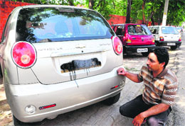 A resident shows the defaced number plate of his car at Sector 32, Chandigarh, on Sunday.