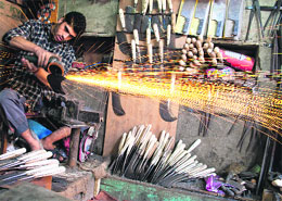 An iron smith sharpens the edge of a knife at his shop in Srinagar on Sunday. 
