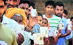 Villagers show their voter cards before casting their ballot during the zila parishad elections at Gill village near Ludhiana