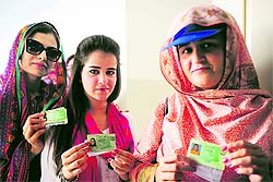 Voters display their identity cards during the re-poll in Karachi on Sunday