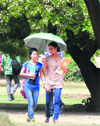 Young girls protect themselves from the blazing sun with an umbrella in Ludhiana on Monday. 