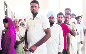 Voters wait for their turn to cast vote at a polling booth in Rupana village on Monday. 