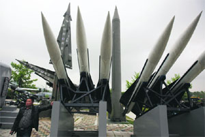 A visitor stands next to a display of mock South Korean US-made Hawk surface-to-air missiles and a mock North Korean Scud-B ballistic missile (in gray) in Seoul on Monday.