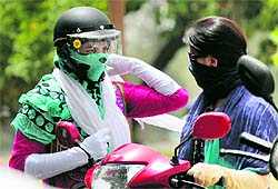 Scooterists cover themselves to protect against the heat in Jammu on Tuesday