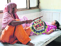 A woman uses a hand fan to provide relief to her daughter from the scorching heat at Lord Mahavir Civil Hospital in Ludhiana. Photo: Inderjeet verma