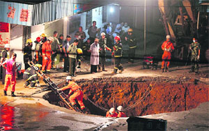 A rescue worker climbs down a ladder to search for survivors in a road cave-in at Shenzhen, Guangdong province of China, on Tuesday. Three persons were killed in the road collapse, the cause of which is currently under investigation.  Reuters 
