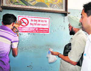 Workers install no-smoking signages at Bathinda bus stand on Wednesday. 