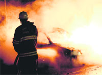 Firemen extinguish a car set on fire by rioters in Kista near Stockholm on Wednesday.  AFP
