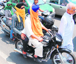 Commuters cover their faces while riding a bike on a hot summer afternoon in Amritsar on Thursday