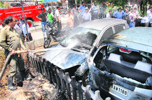 Firemen douse flames in the cars that were burnt due to burning of garbage in Jalandhar on Thursday. 