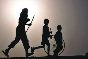 Children play with a cycle rim during evening time at a village in Karnal. 