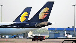 An India Post mail van moves past a parked Jet Airways passenger plane at the Delhi international airport. Jet shareholders approved an agreed sale of a 24% stake in the airline for US $370 million to Abu Dhabi's Etihad Airways, a senior executive of the Indian carrier said on Friday