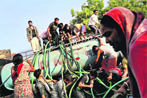 As taps run dry, people collect drinking water from a government tanker at a slum in New Delhi on Friday.