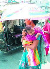 A woman carries an umbrella to save her child from the scorching heat in Amritsar. 