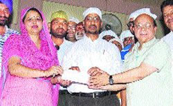 Industry Minister Anil Joshi hands over a cheque to Mandeep Kaur, Principal, Government Senior Secondary School (Girls), Mall Road, in Amritsar on Saturday. 